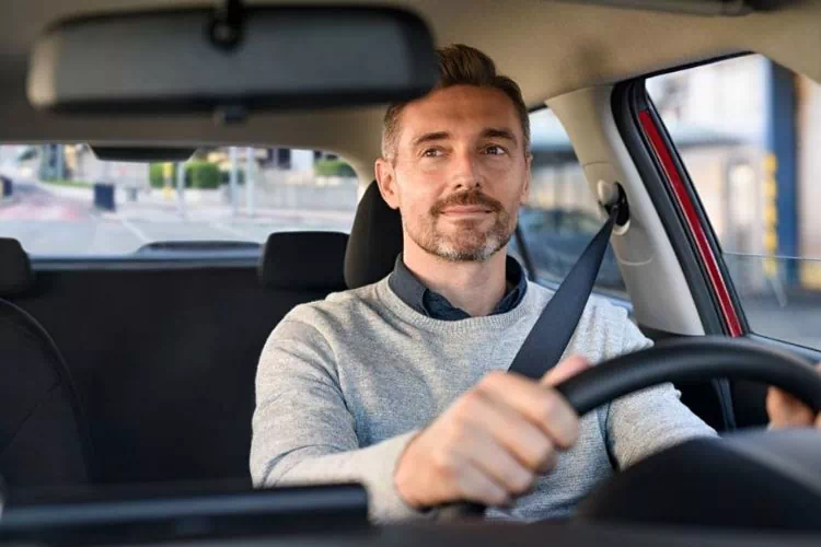 Homme conduisant sa voiture de manière décontractée, en confiance
