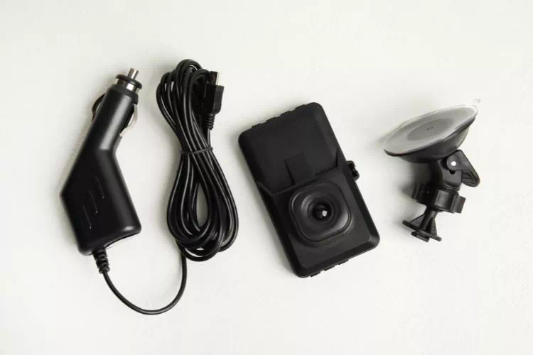Une caméra embarquée et ses accessoires : pied et cordon d'alimentation à brancher dans allume-cigare