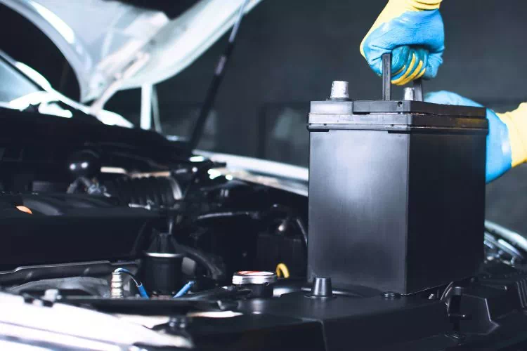 Homme en train d'enlever la batterie de sa voiture