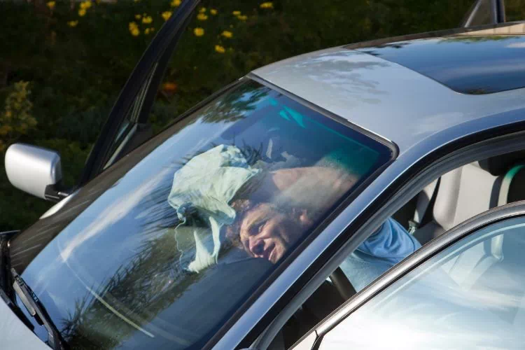 Homme dégraissant l'intérieur de son pare-brise