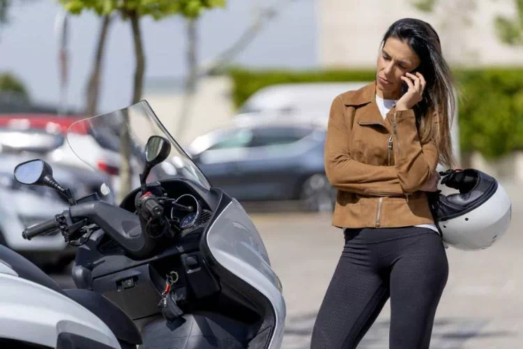 Jeune femme au téléphone à côté de son scooter