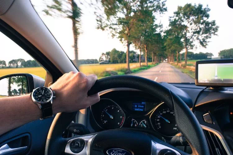 Homme au volant d'une voiture sur une route de campagne