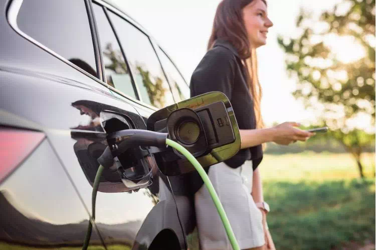 Femme en train de recharger sa voiture hybride ou électrique