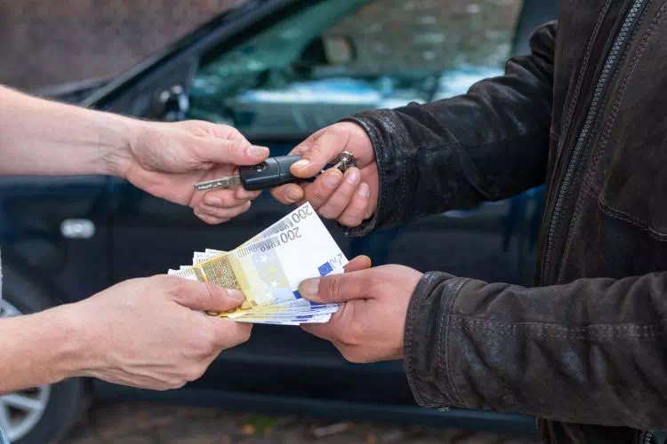 Personne vendant sa voiture cash et remettant les clés