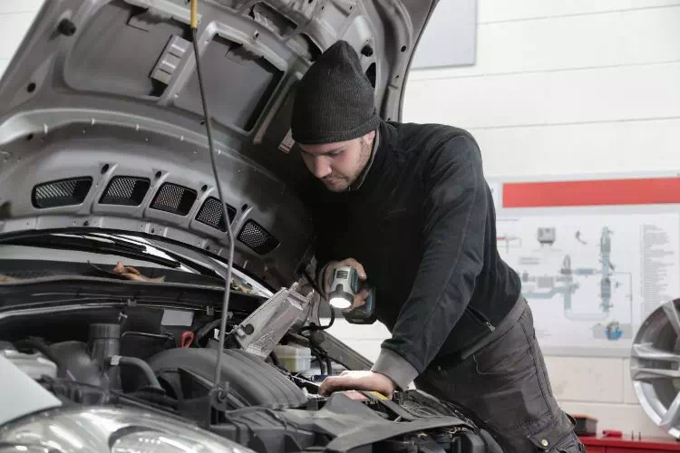 Homme vérifiant le moteur d'une voiture d'occasion
