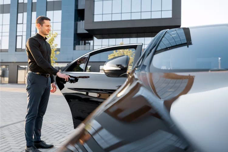 Chauffeur VTC ouvrant la portière pour faire descendre un client ou une cliente