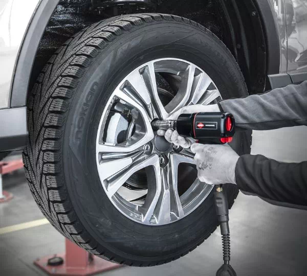 Mécanicien en train de regonfler un pneu avec un compresseur
