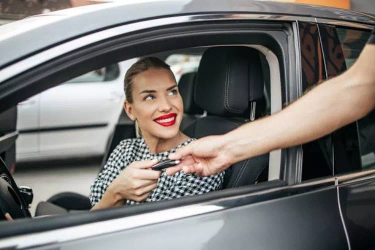 Femme prenant une voiture de location et recevant les clés du loueur