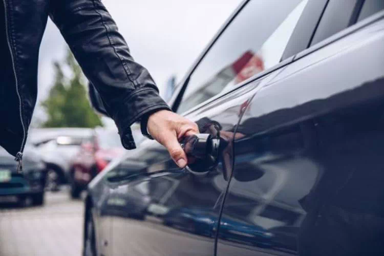 Homme ouvrant la porte de la voiture qu'il vient de prendre en location