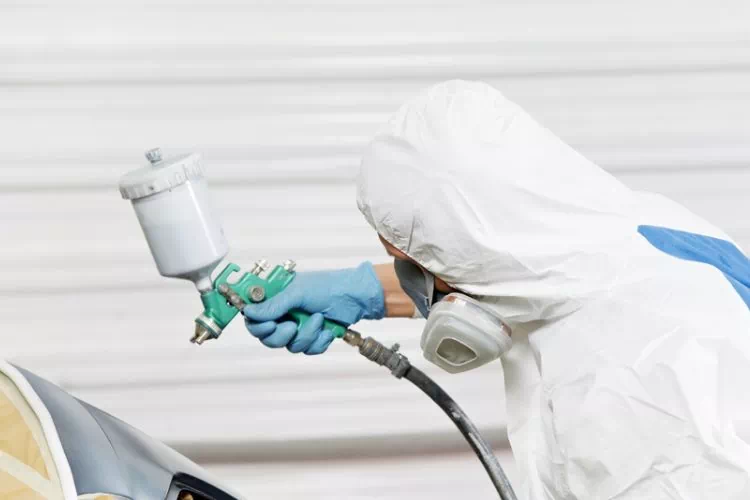 Personne peignant un élément de voiture au pistolet