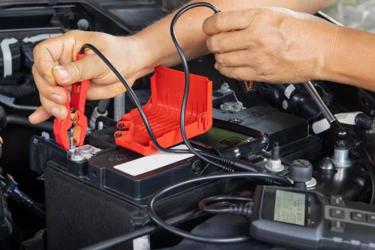 Personne testant une batterie AGM sur sa voiture