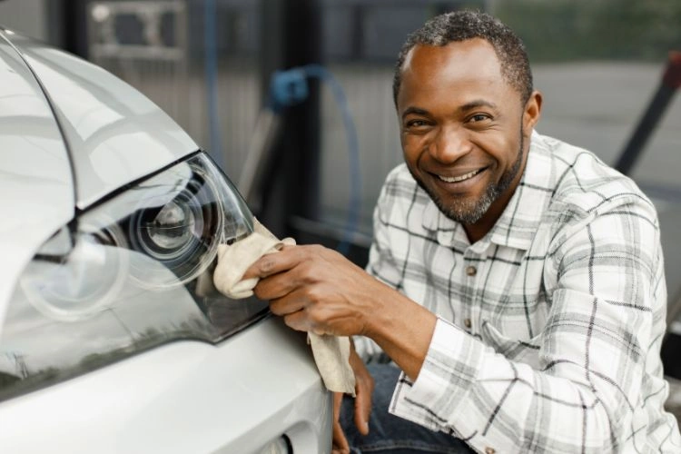 Homme en train d'entretenir les phares de son véhicule