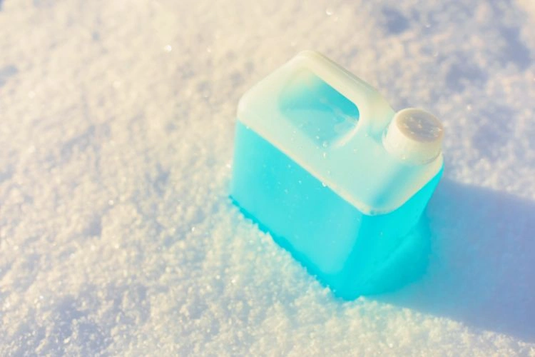 Bidon de lave-glace par terre en pleine neige