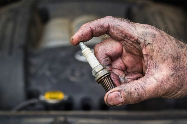 Main sale tenant une bougie d'allumage pour représenter quand il faut la changer