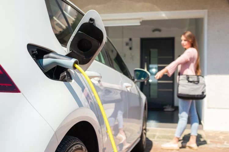 Femme qui a garé sa voiture devant chez elle et l'a mise à recharger
