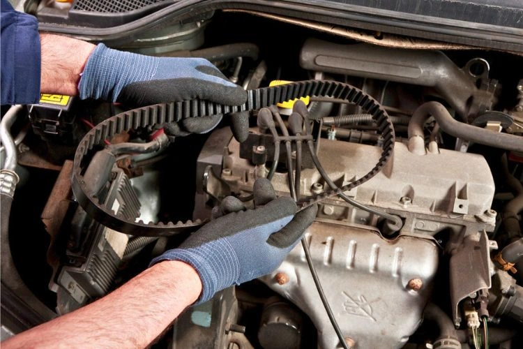 Homme tenant une courroie de distribution pour représenter l'importance de la changer