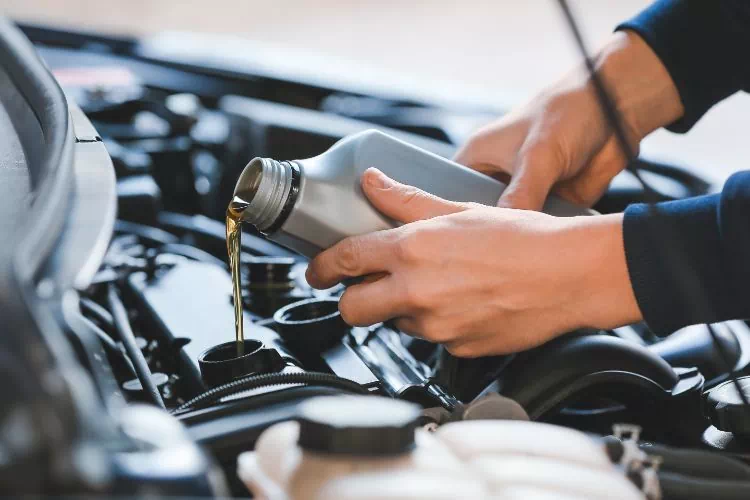 Mécanicien remplissant le moteur d'une voiture avec de l'huile