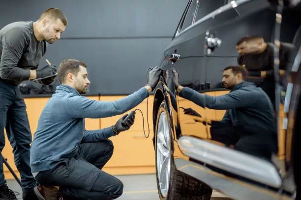 Homme inspectant la carrosserie d'une voiture