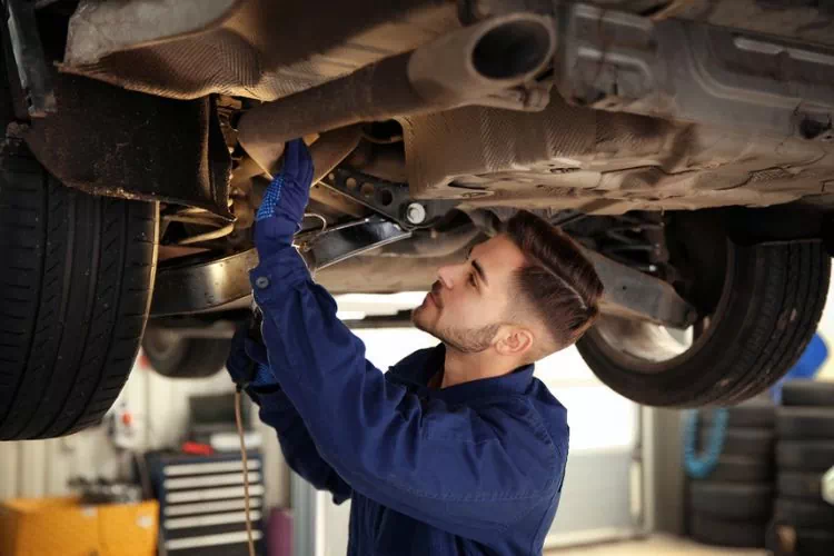 Mécanicien inspectant le dessous du châssis d'une voiture
